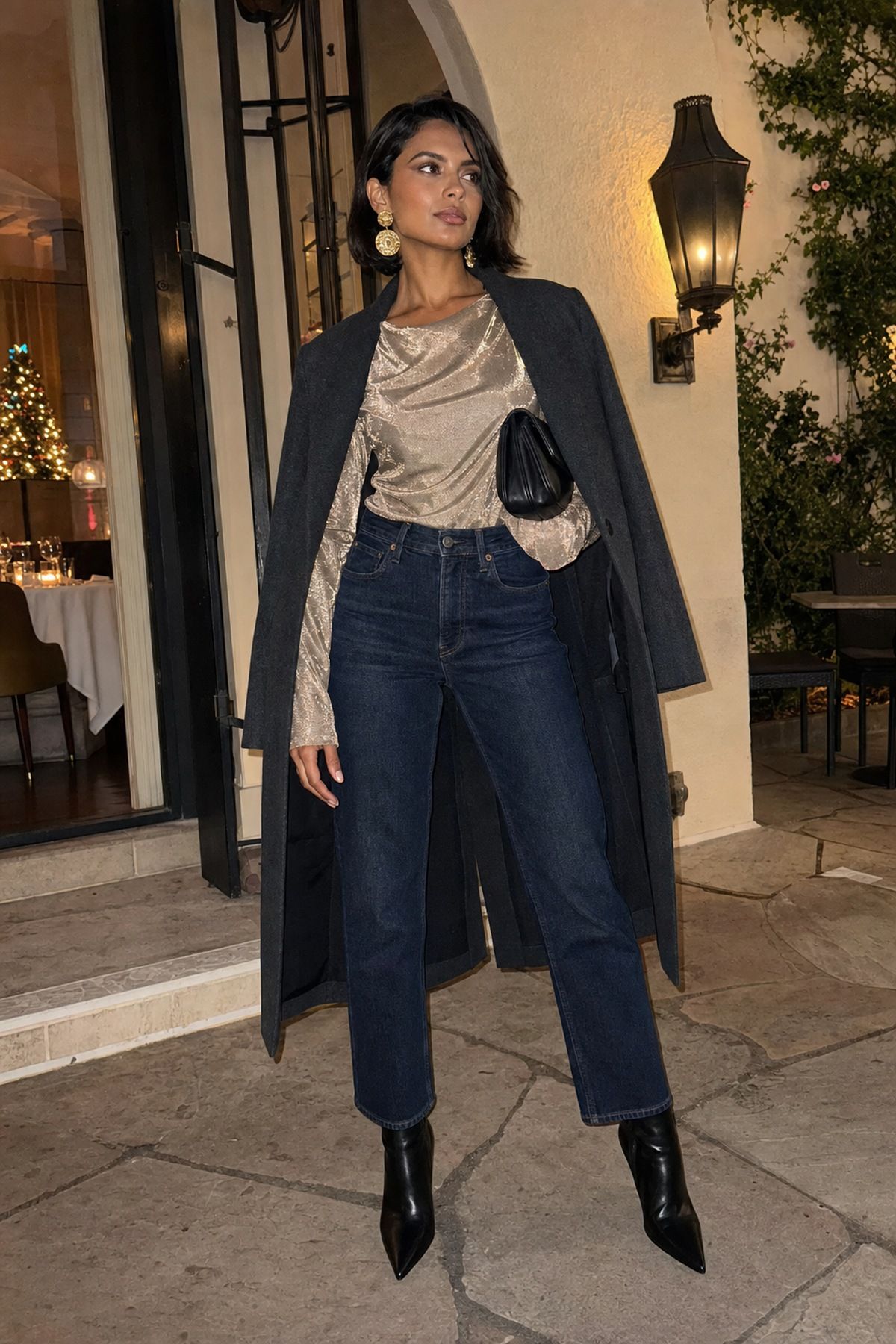 Woman wearing a metallic top with dark jeans and a statement earring, a casual Christmas outfit