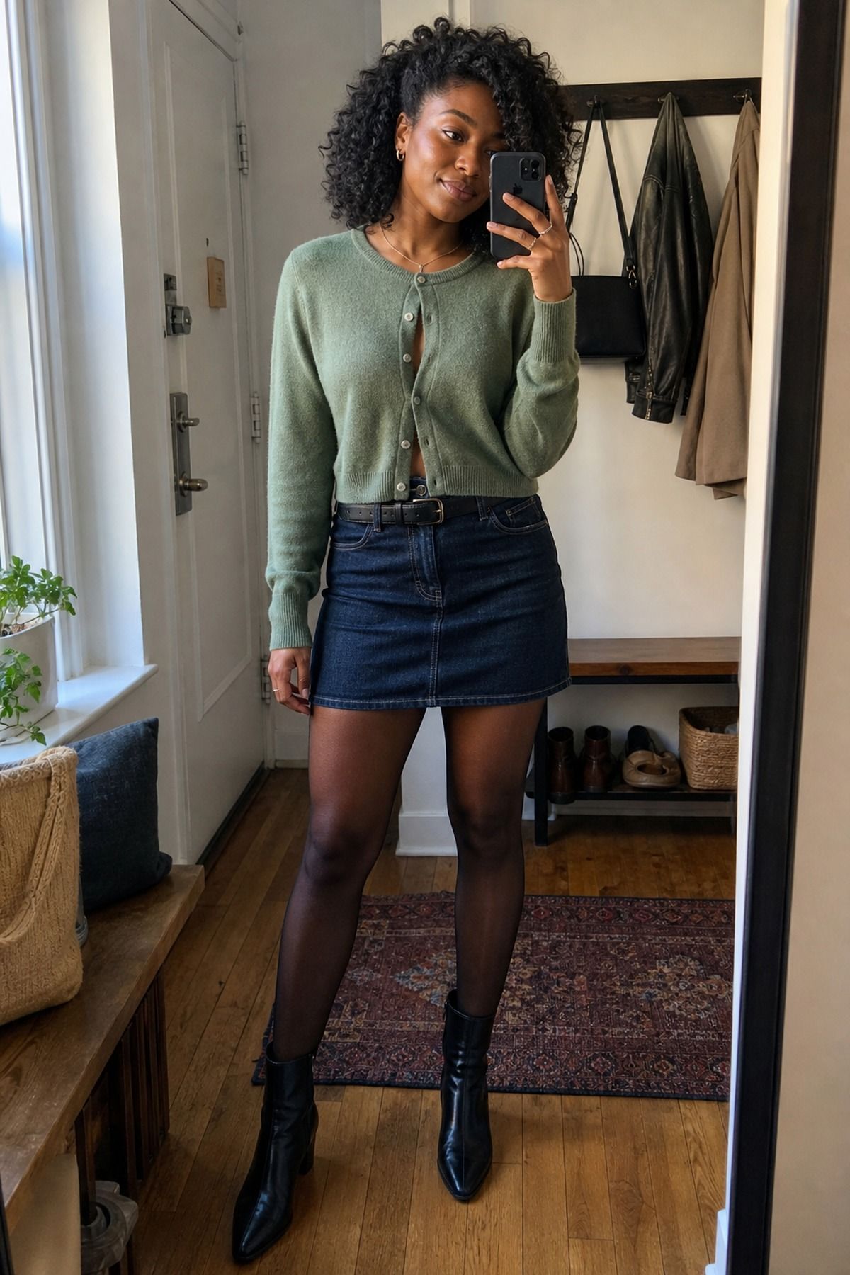 Woman wearing a cropped cardigan with a denim mini and ankle boots, a casual fall denim skirt outfit