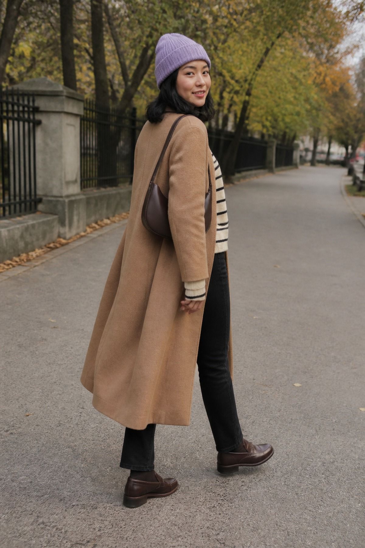 Woman wearing a long coat with a beige striped sweater and black jeans black jeans