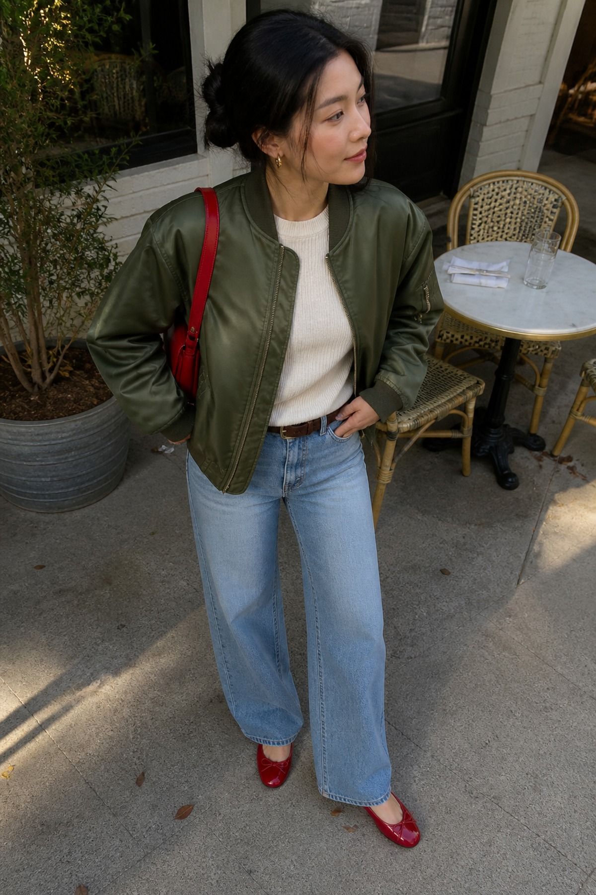 Woman wearing a bomber jacket with wide-leg jeans and a cream knit, a fall brunch outfit