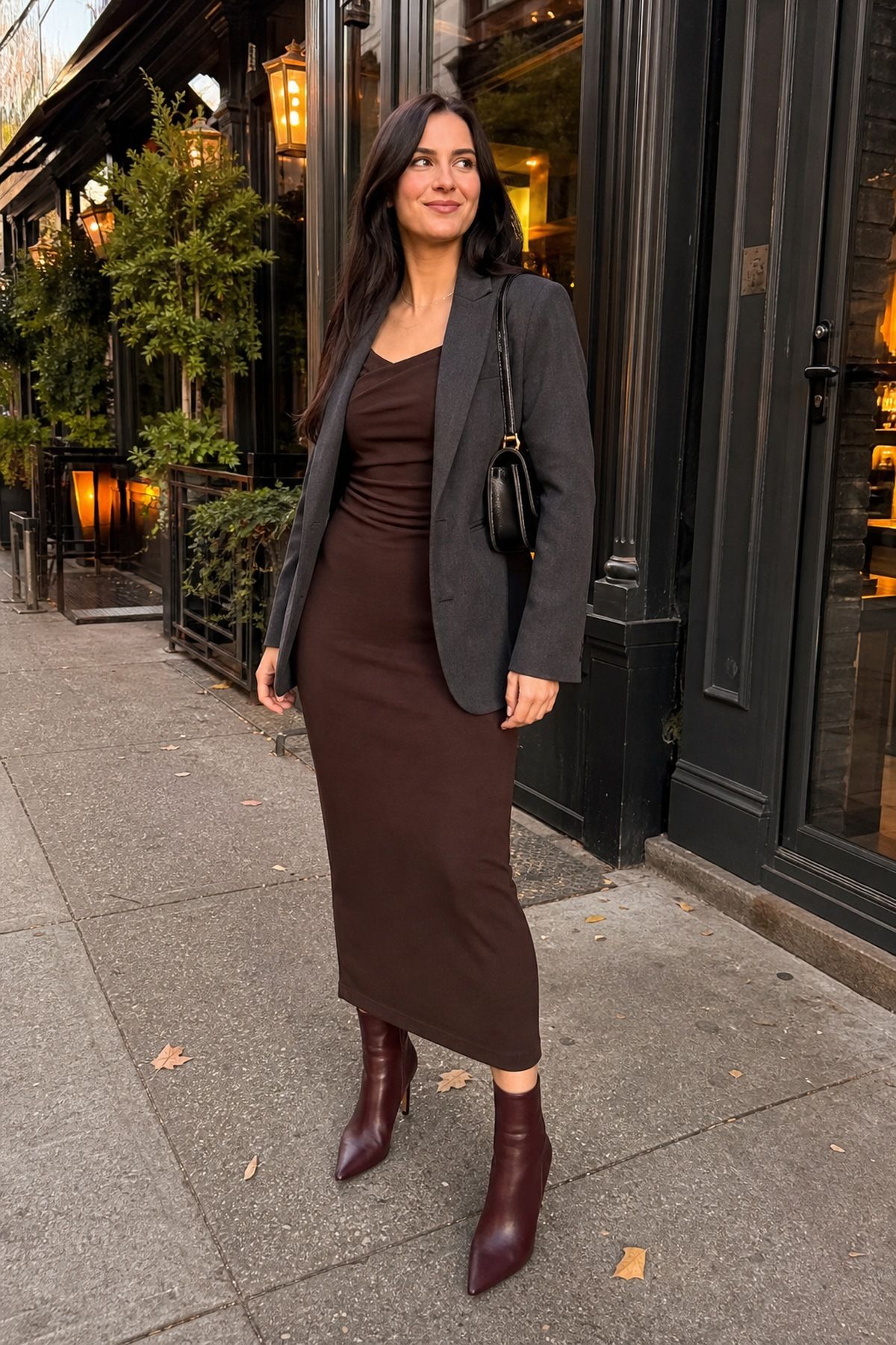Woman wearing a midi dress with boots and a fitted blazer, a fall wedding guest outfit
