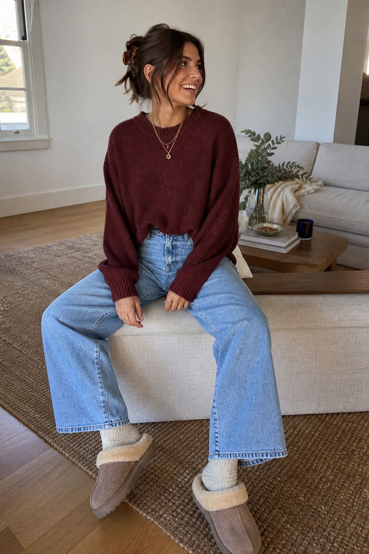 Woman wearing a maroon sweater with wide-leg jeans and slippers