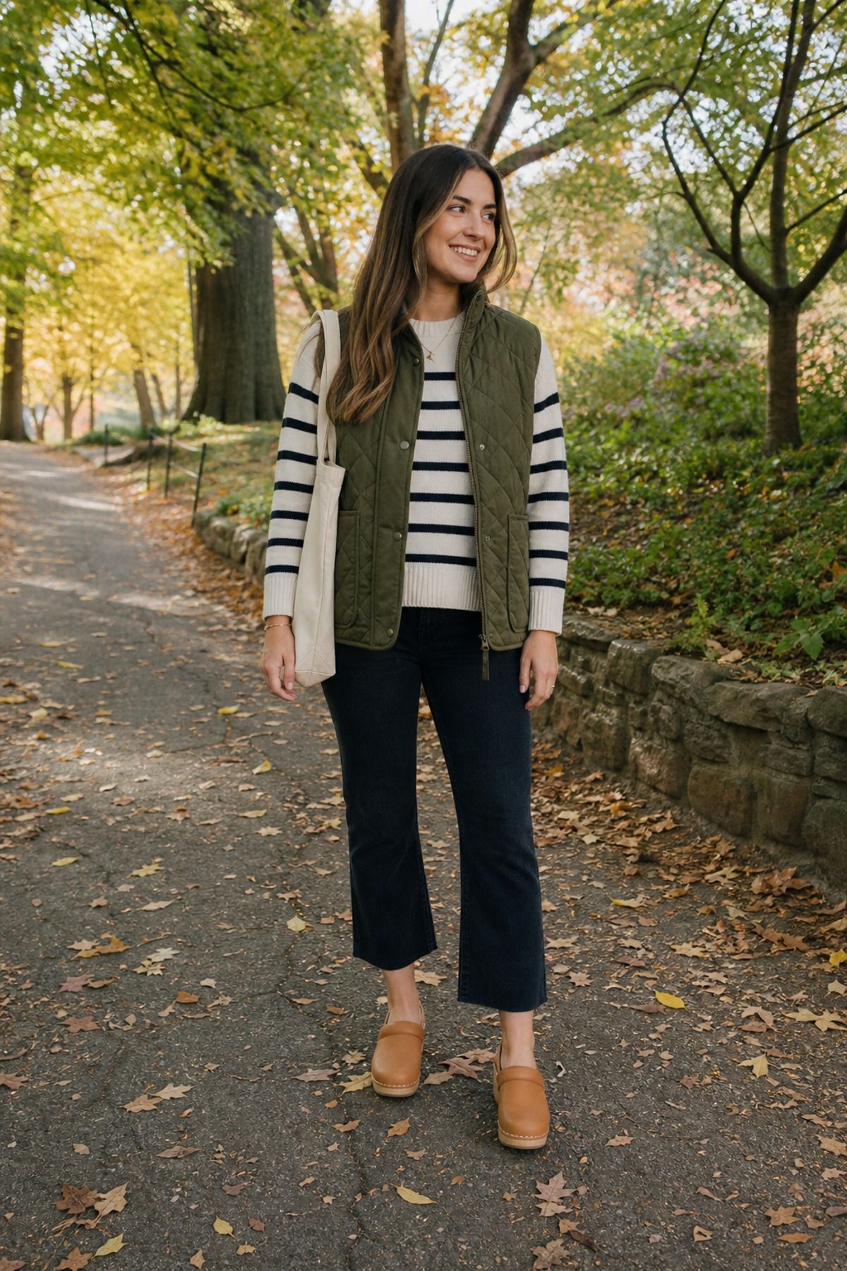 Woman wearing a quilted vest with a striped sweater, a 60 degree weather outfit