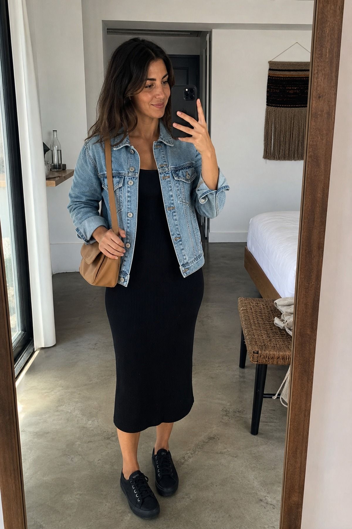 Woman wearing a black midi dress with a denim jacket, a city vacation outfit