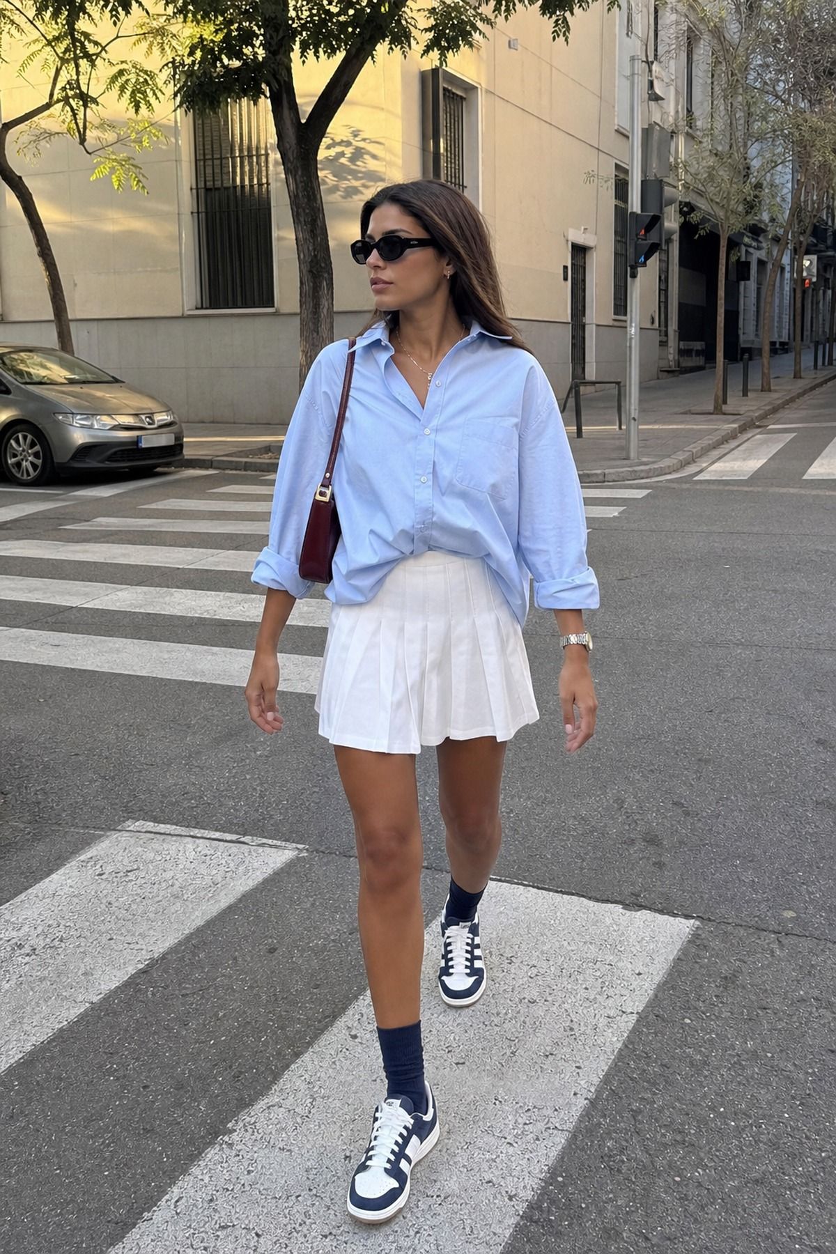 Woman wearing a skirt with a button down shirt, a skirt and sneakers outfit