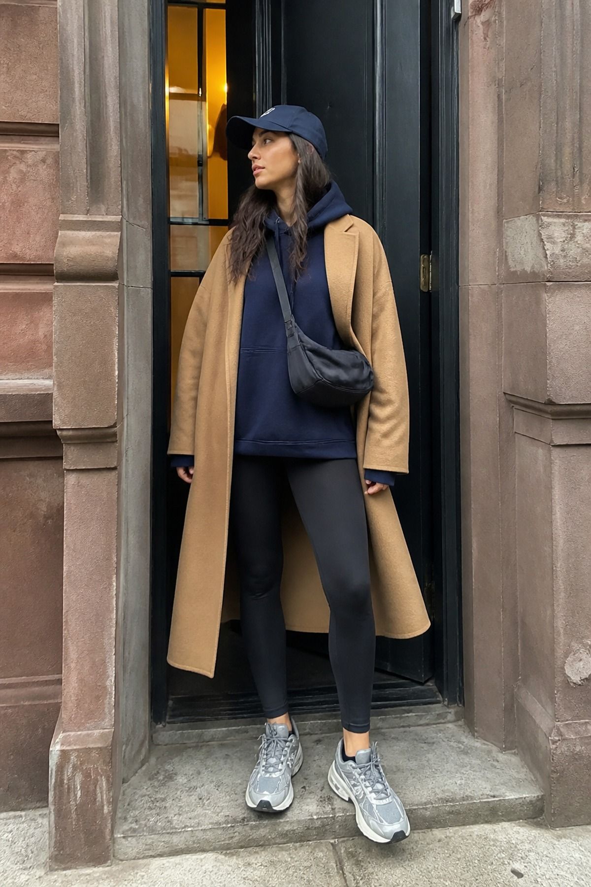 Woman wearing an oversized hoodie with leggings and a long coat