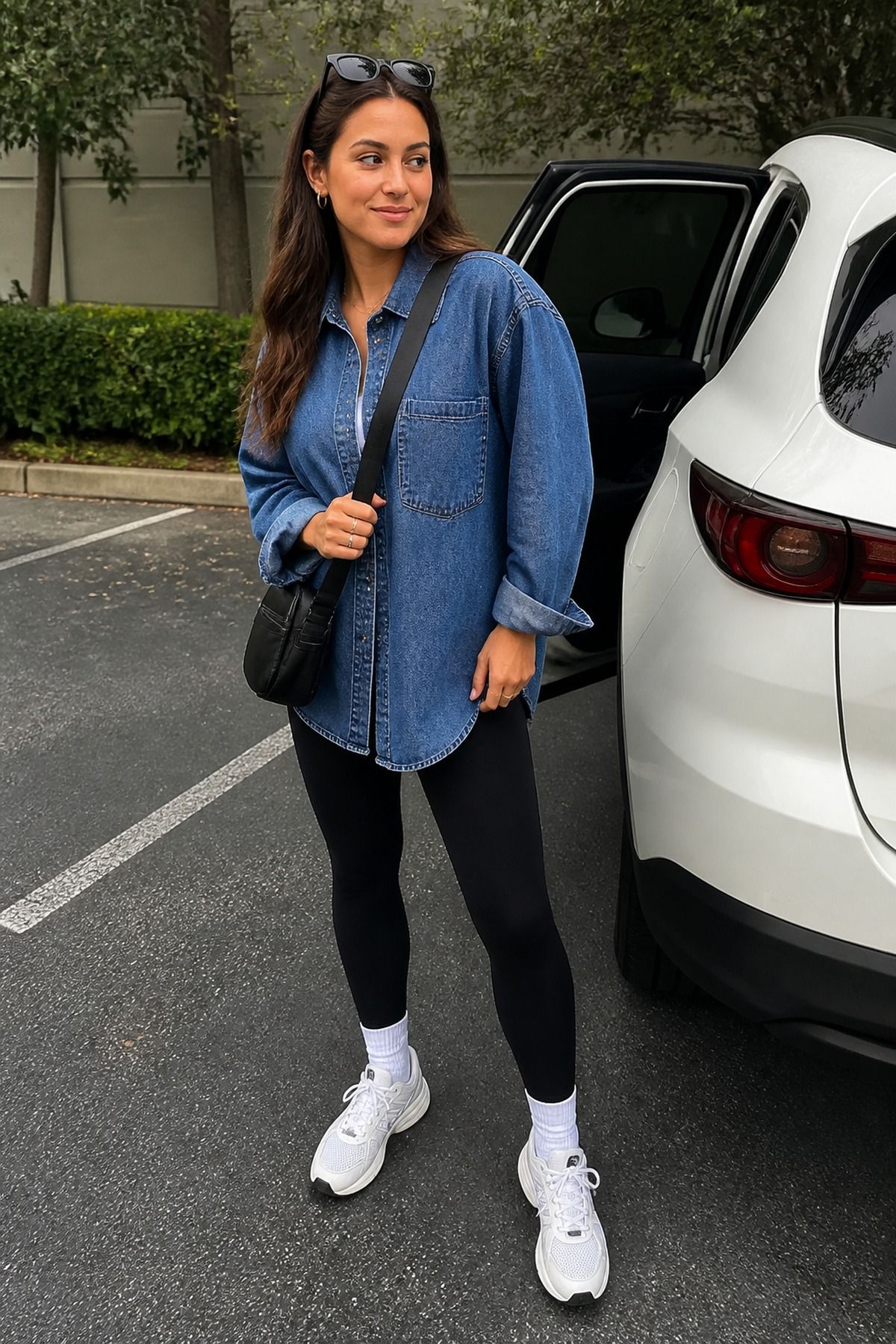 Woman wearing an oversized denim shirt with black leggings