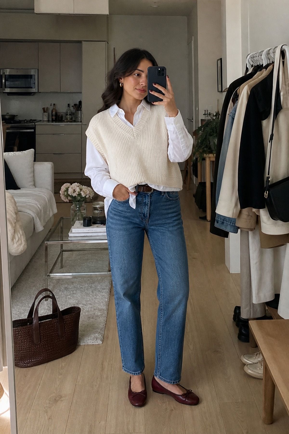 Woman wearing a sweater vest with a white button-down and straight jeans