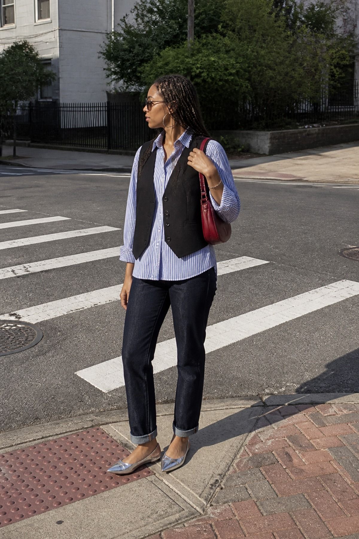 Woman wearing a tailored vest over a striped shirt and denim