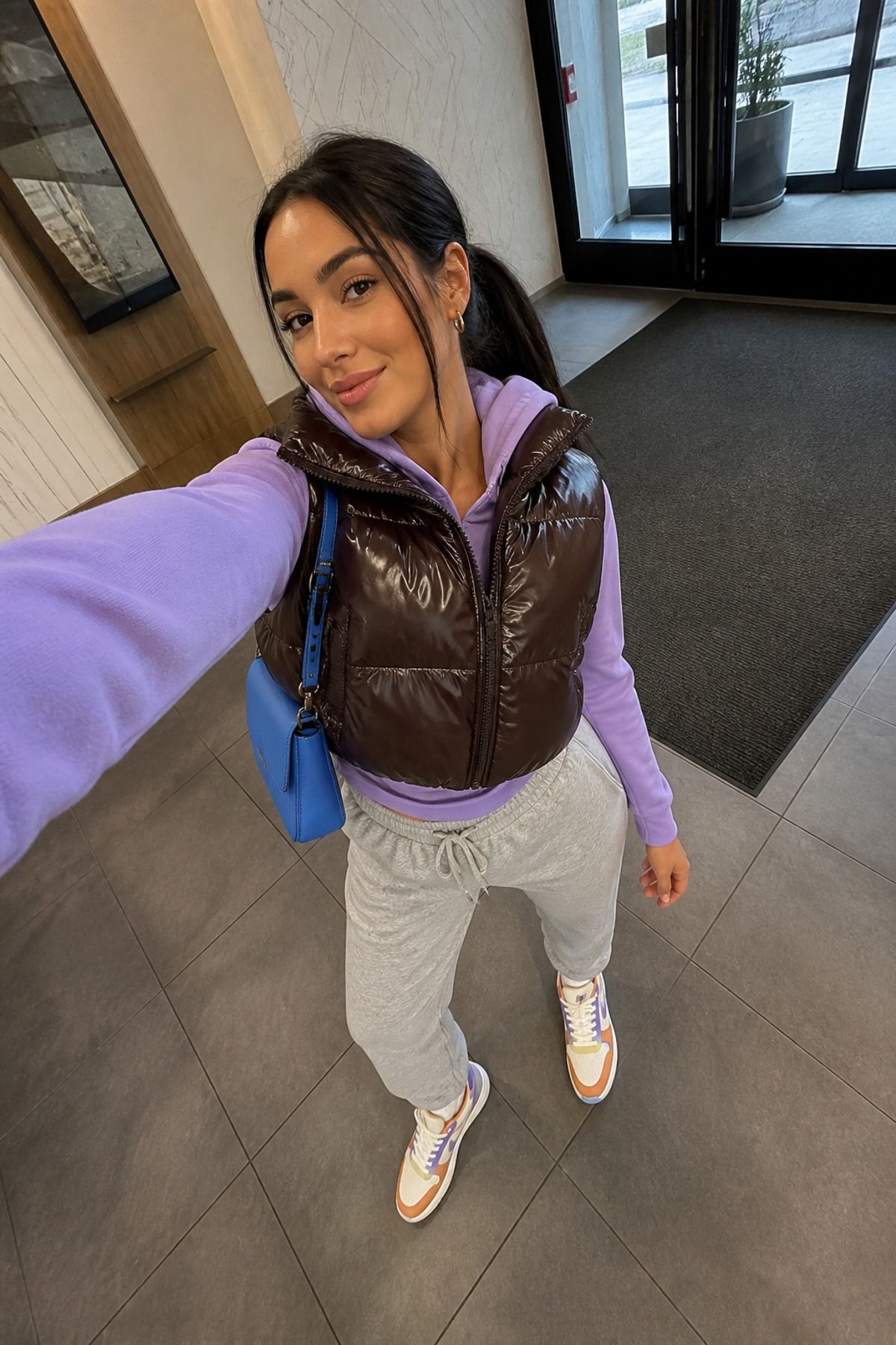 Woman wearing a cropped puffer vest with joggers and retro sneakers
