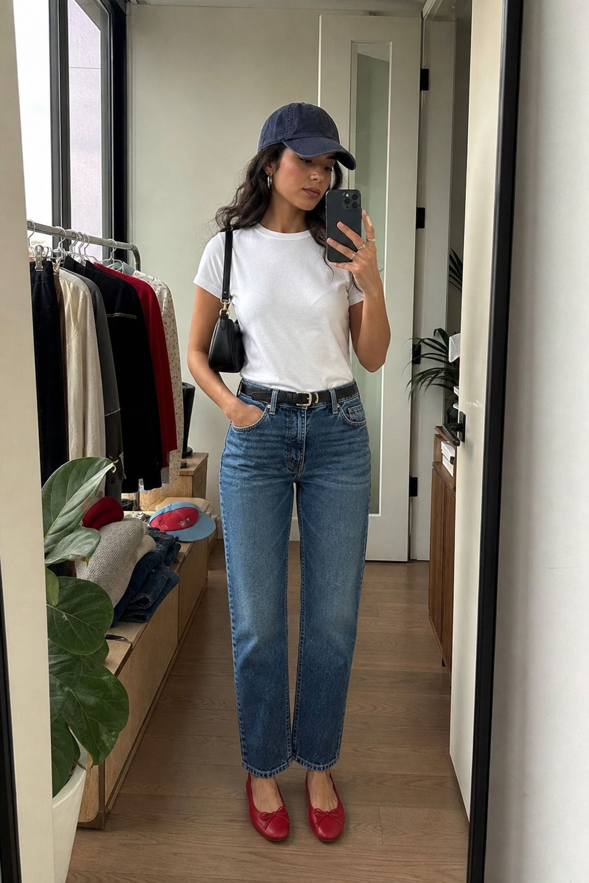 Woman wearing a white tee and straight jeans with a baseball cap
