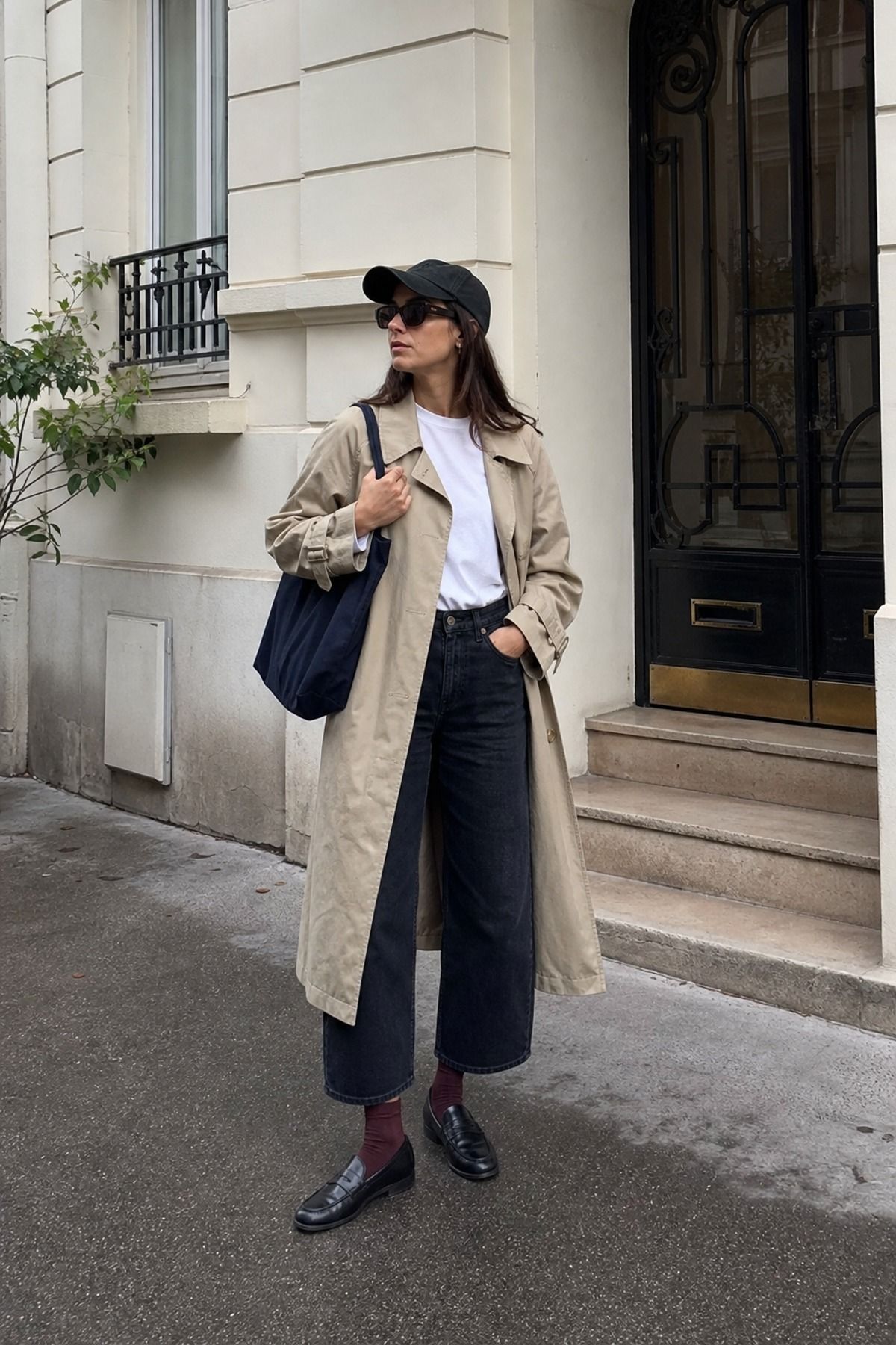 Woman wearing a trench coat outfit with a baseball cap