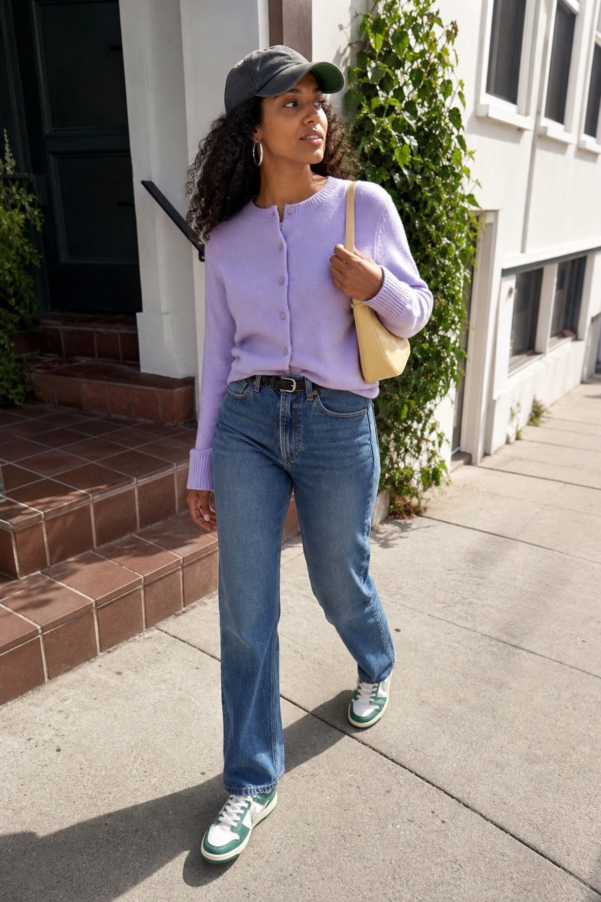 Woman wearing a cardigan and jeans with a baseball cap