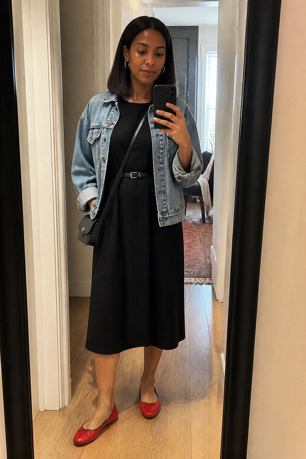 Woman wearing a black dress with a denim jacket, a casual chic outfit