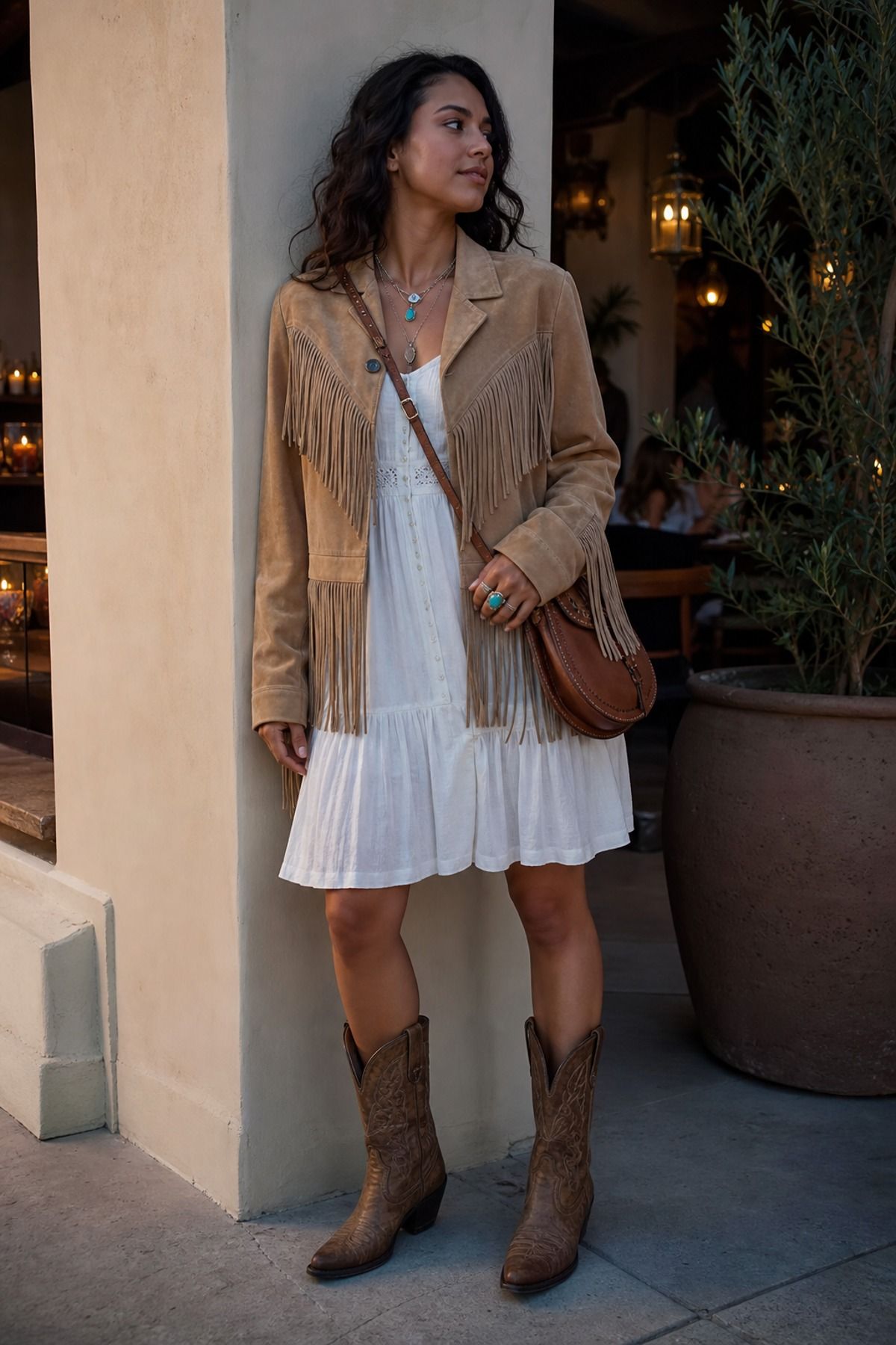 Woman wearing a suede fringe jacket with a cotton dress, a coastal cowgirl outfit