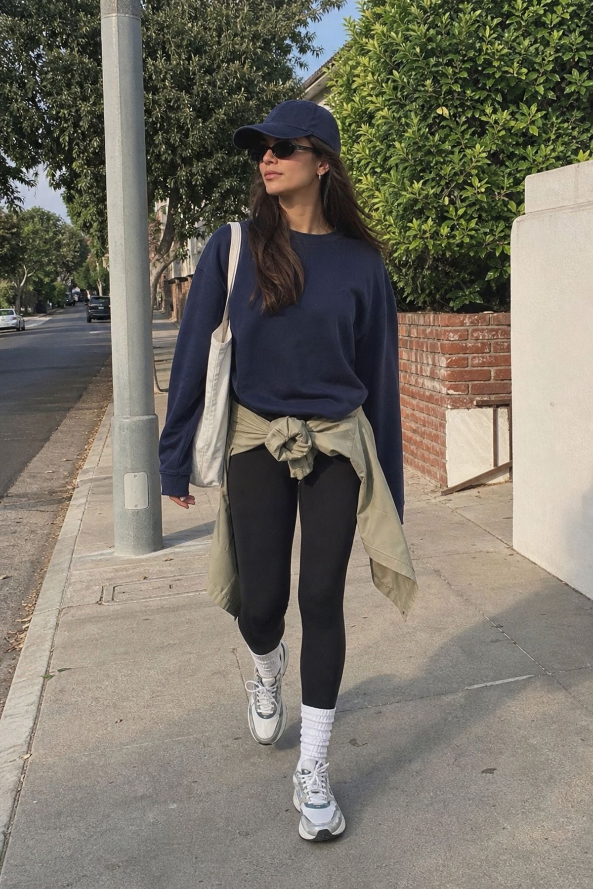 Woman wearing black leggings with tall socks and sneakers, a model off duty outfit