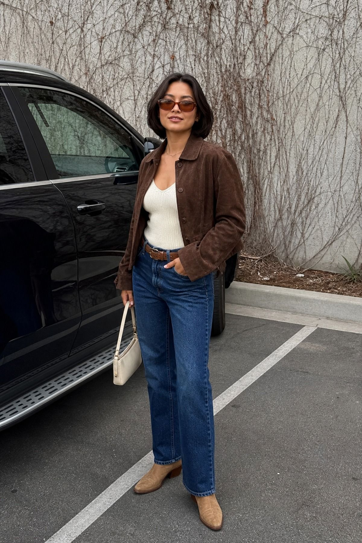 Woman wearing a suede jacket with straight-leg jeans, a model off duty outfit