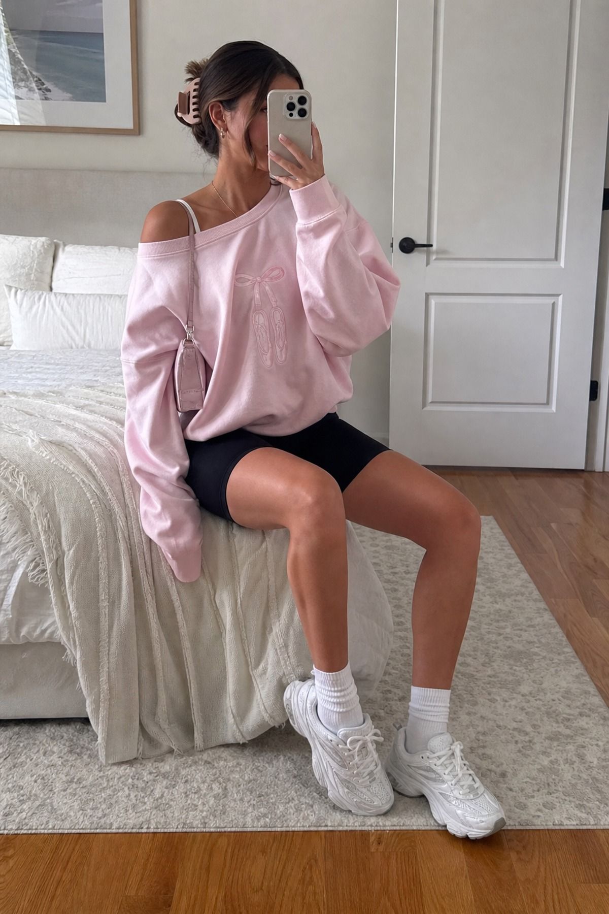 Woman wearing biker shorts with an oversized ballet sweatshirt, a Pilates princess outfit