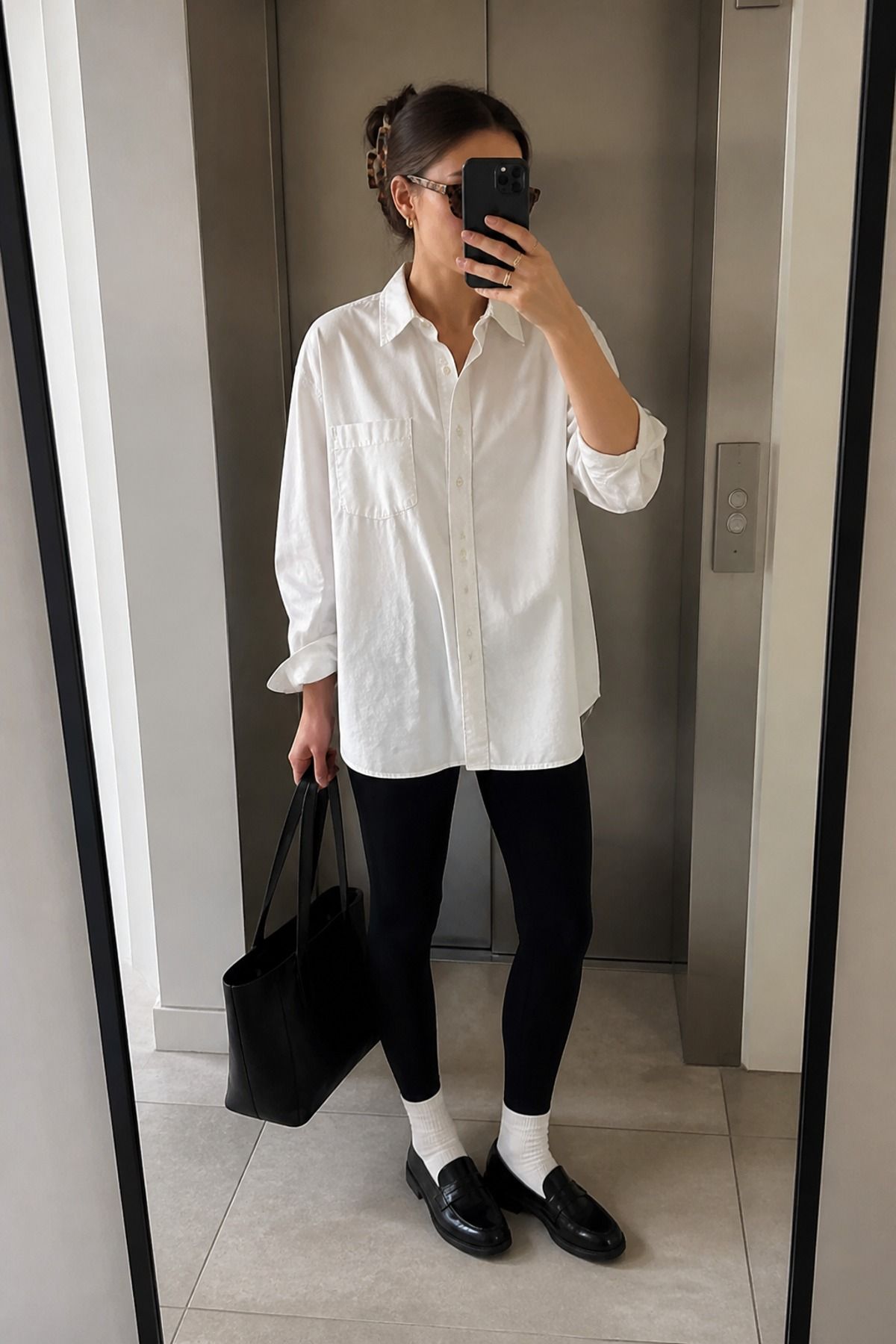 Woman wearing an Oxford shirt with black leggings and loafers, a preppy casual outfit