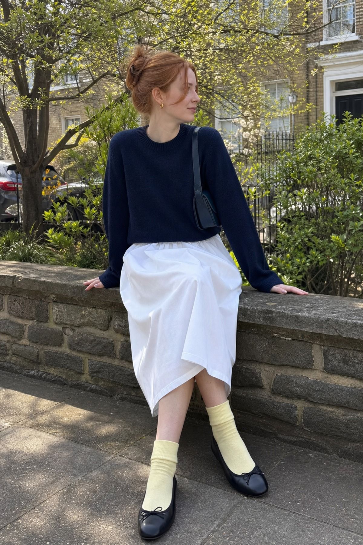 Woman wearing a navy sweater with a poplin skirt, a Scandinavian style outfit
