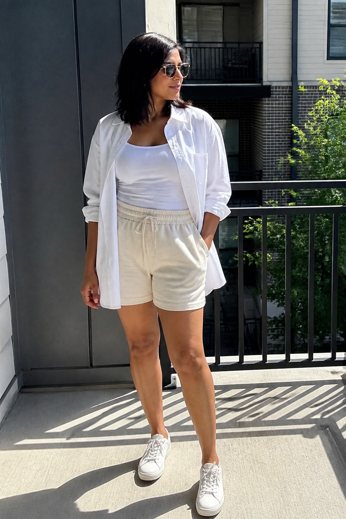 Woman wearing soft shorts with a poplin shirt, a casual mom outfit
