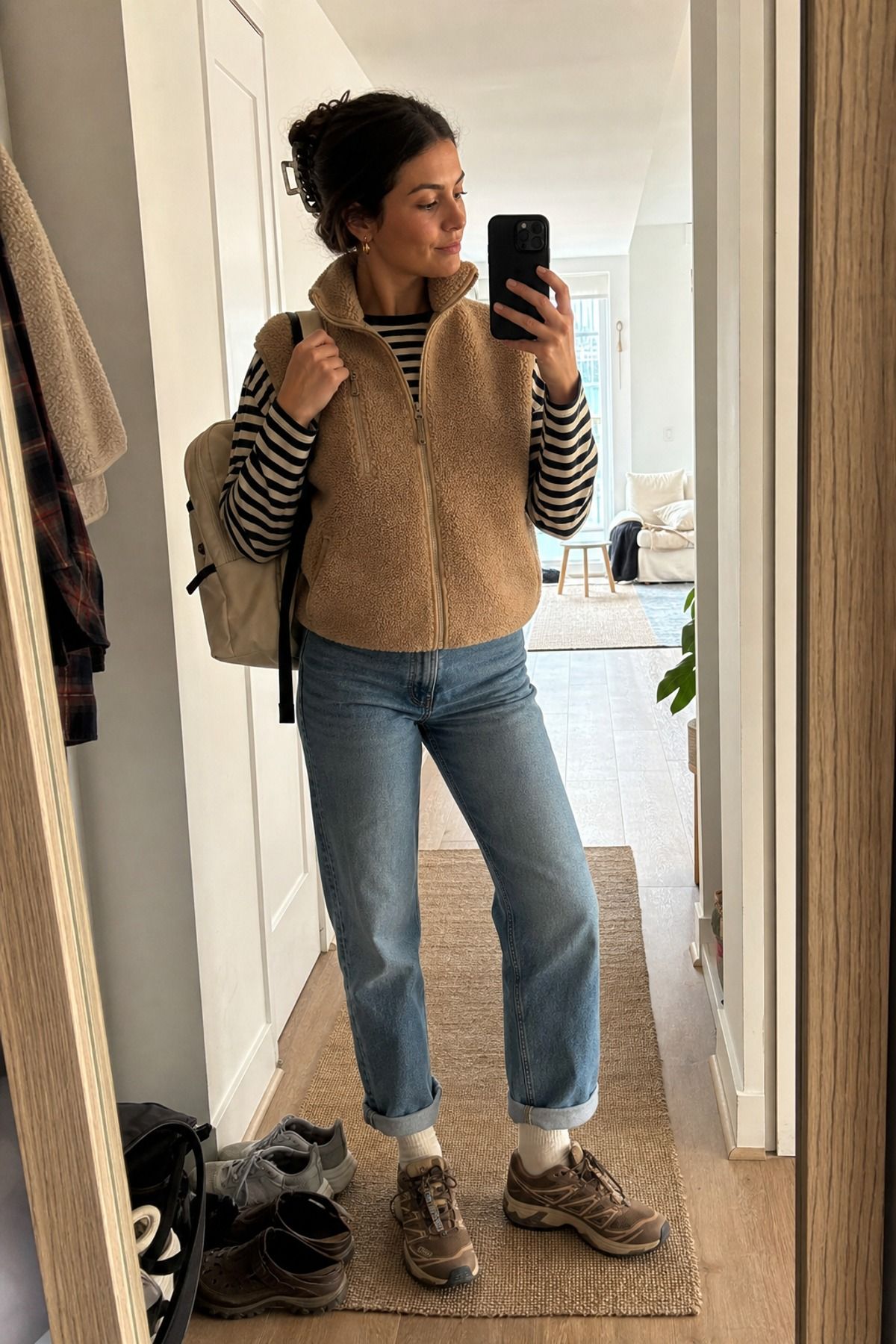 Woman wearing a fleece vest with a striped tee and jeans, a granola girl outfit