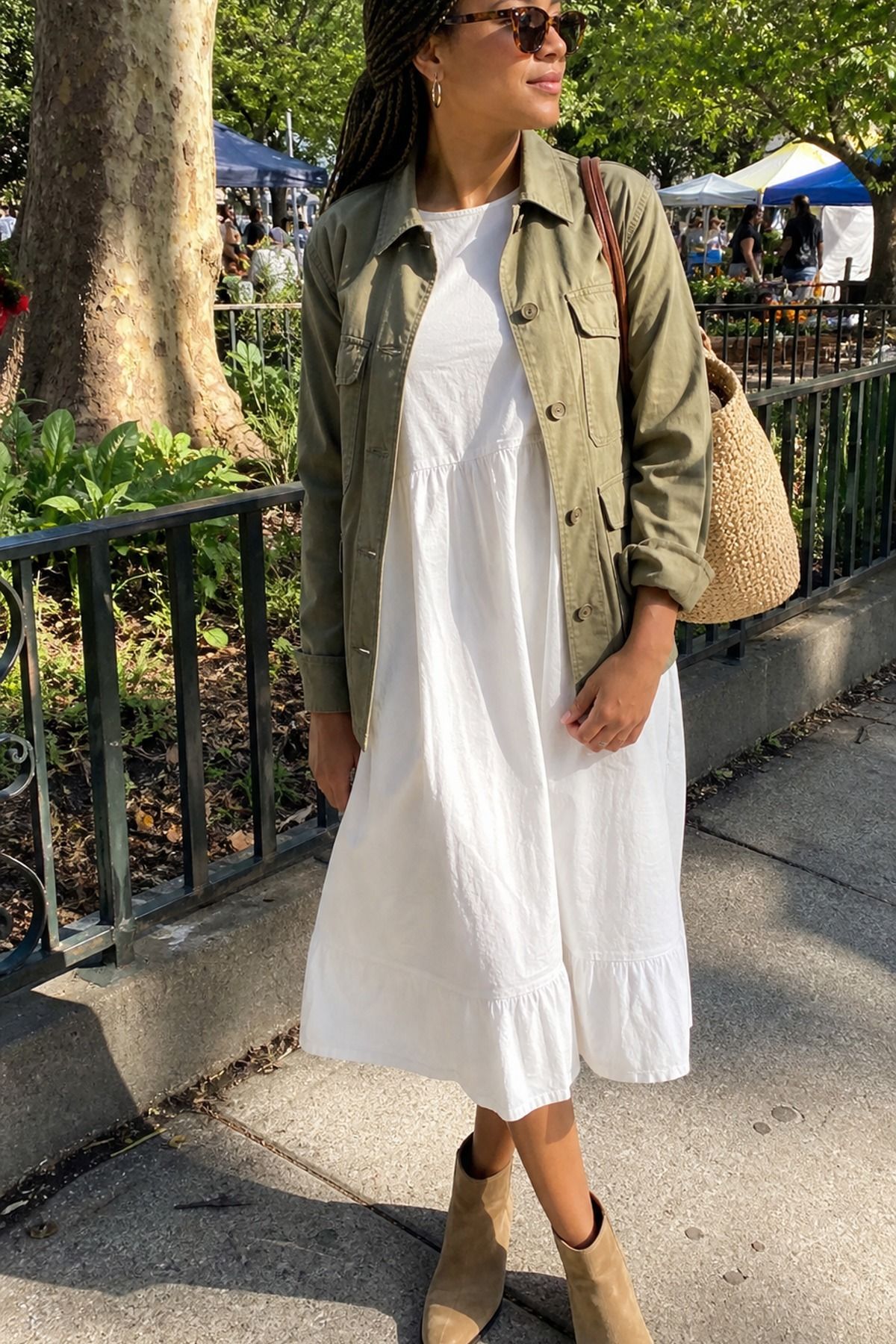 Woman wearing a khaki utility jacket with a white dress