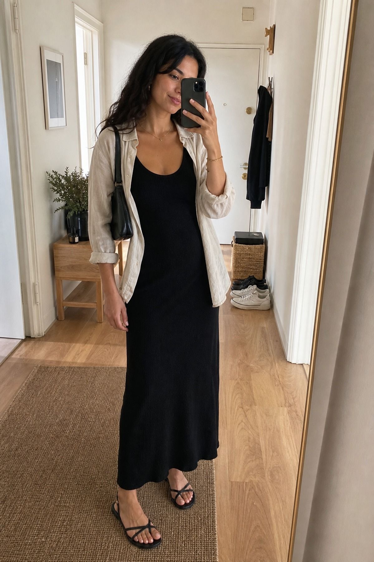 Woman wearing a black tank dress with a linen shirt, an all black outfit