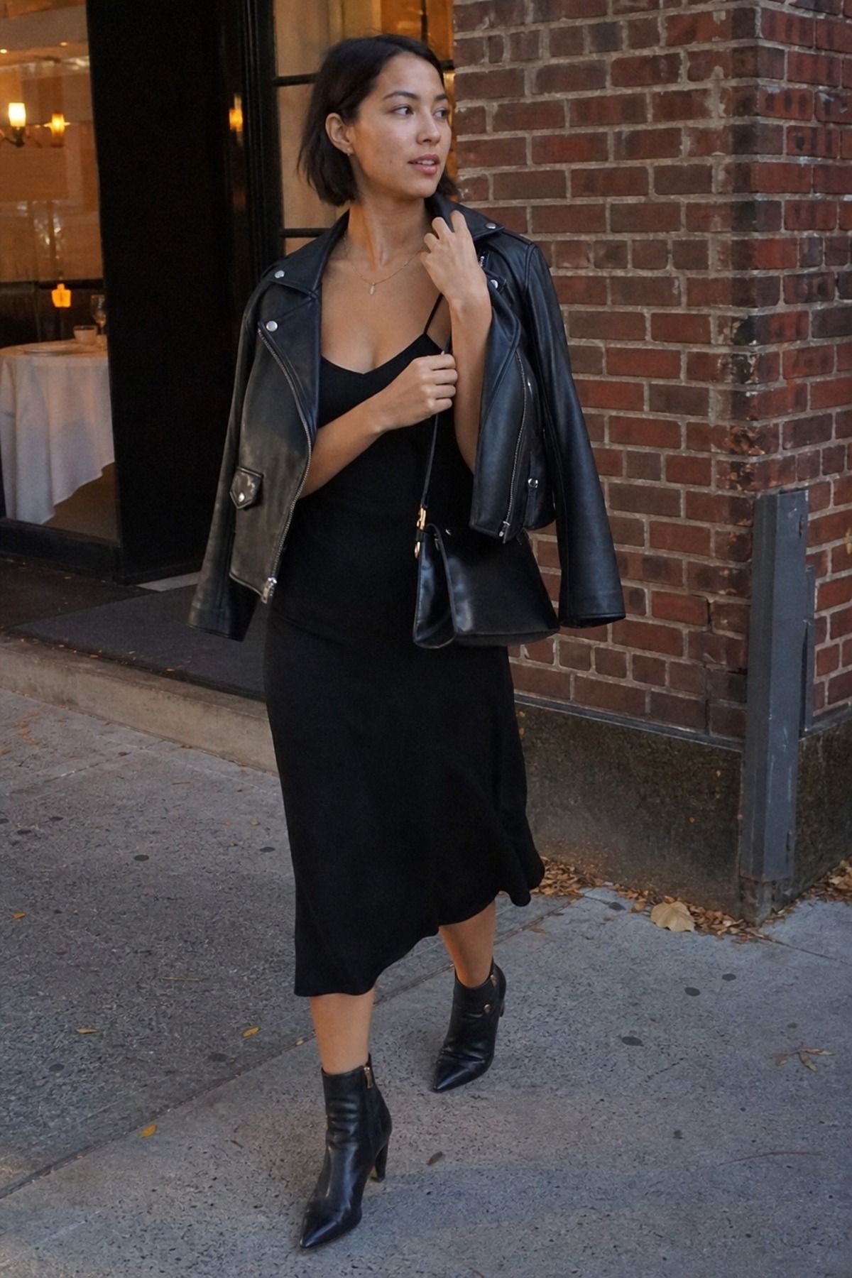 Woman wearing a black leather jacket with a midi dress, an all black outfit