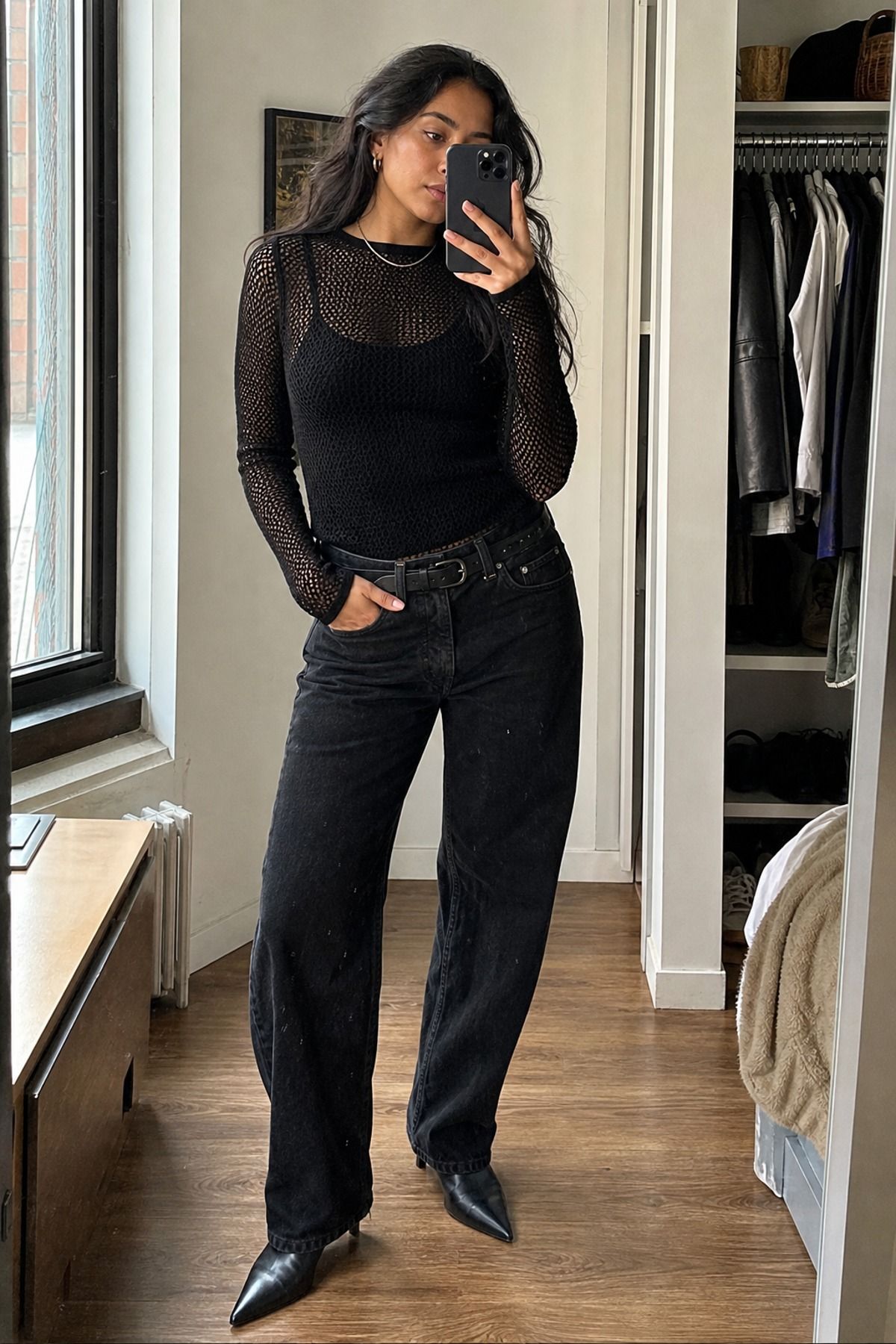 Woman wearing a black mesh top with relaxed jeans, an all black outfit