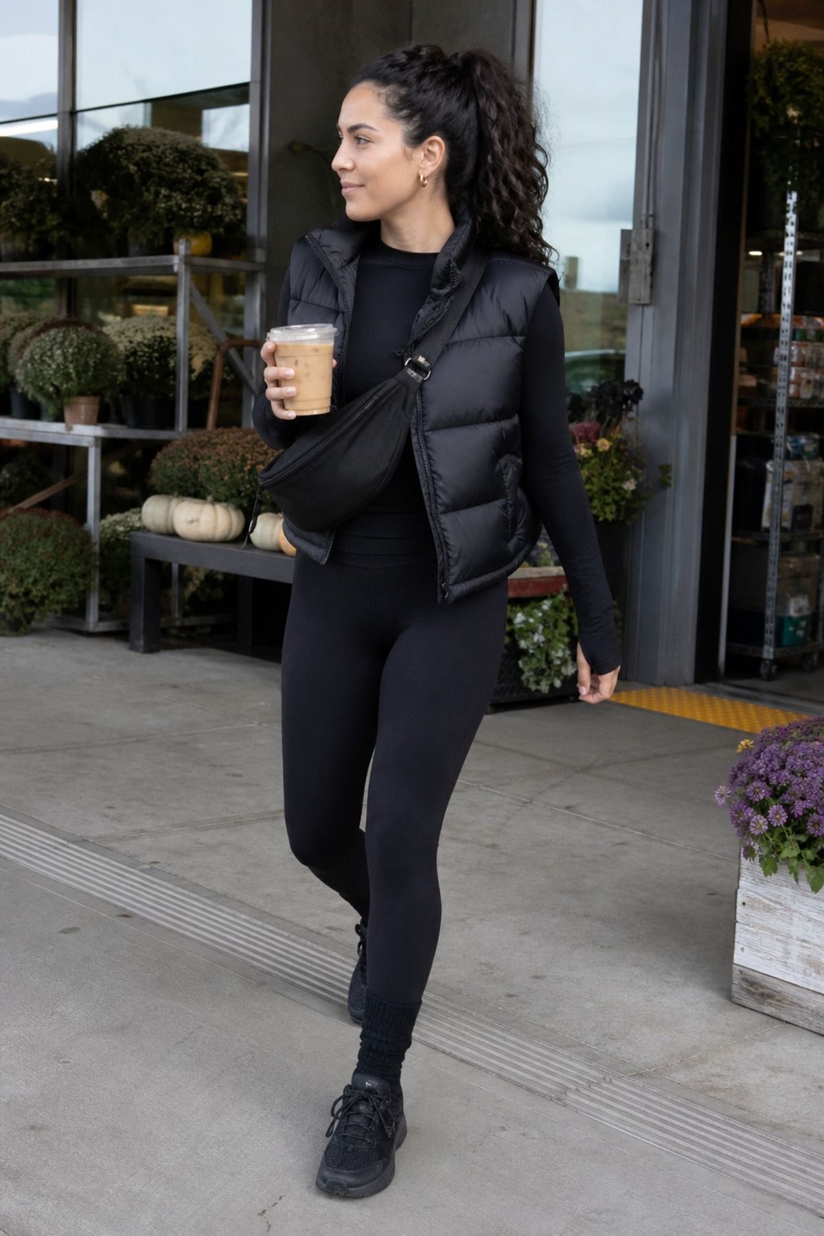 Woman wearing a black puffer vest with leggings, an all black outfit