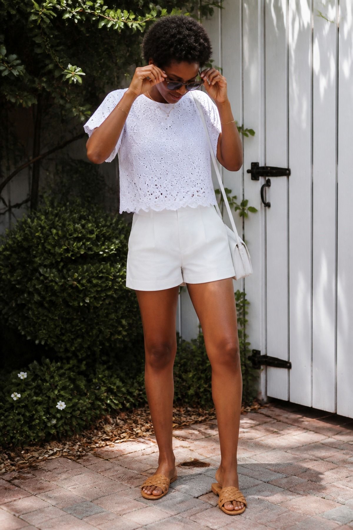 Woman wearing a white eyelet top with white shorts, an all white outfit