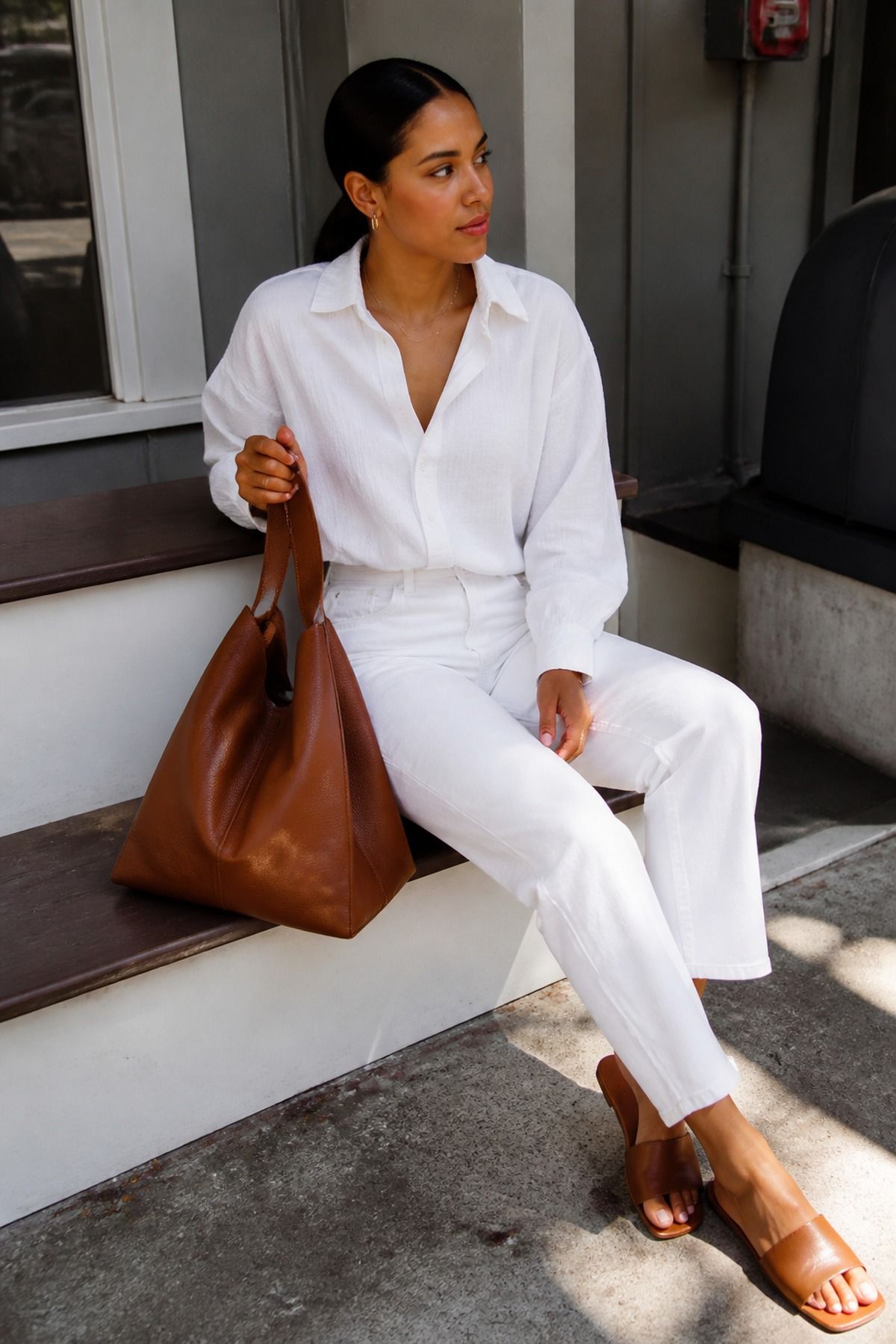 Woman wearing a cognac bag with an all-white outfit, a brown outfit