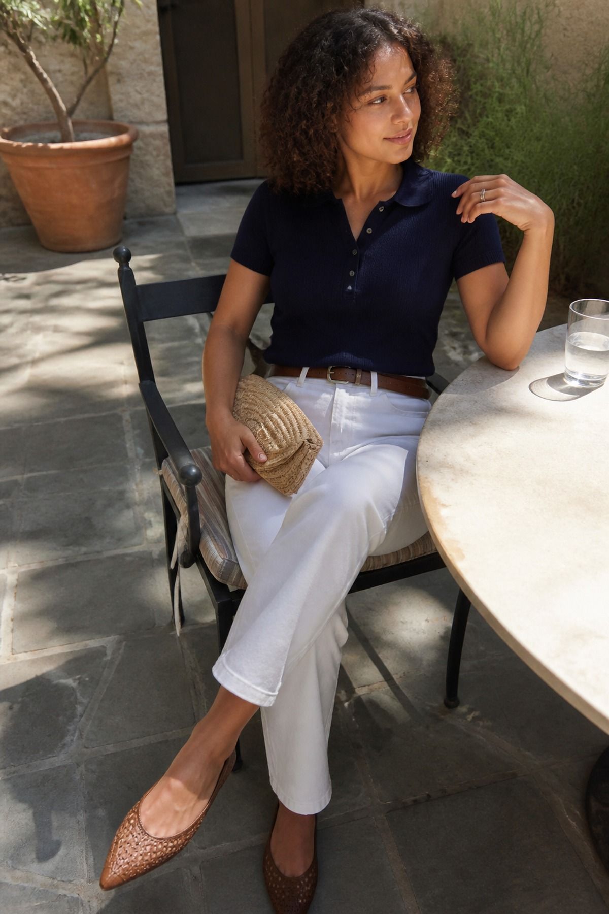 Woman wearing a navy polo knit with white denim