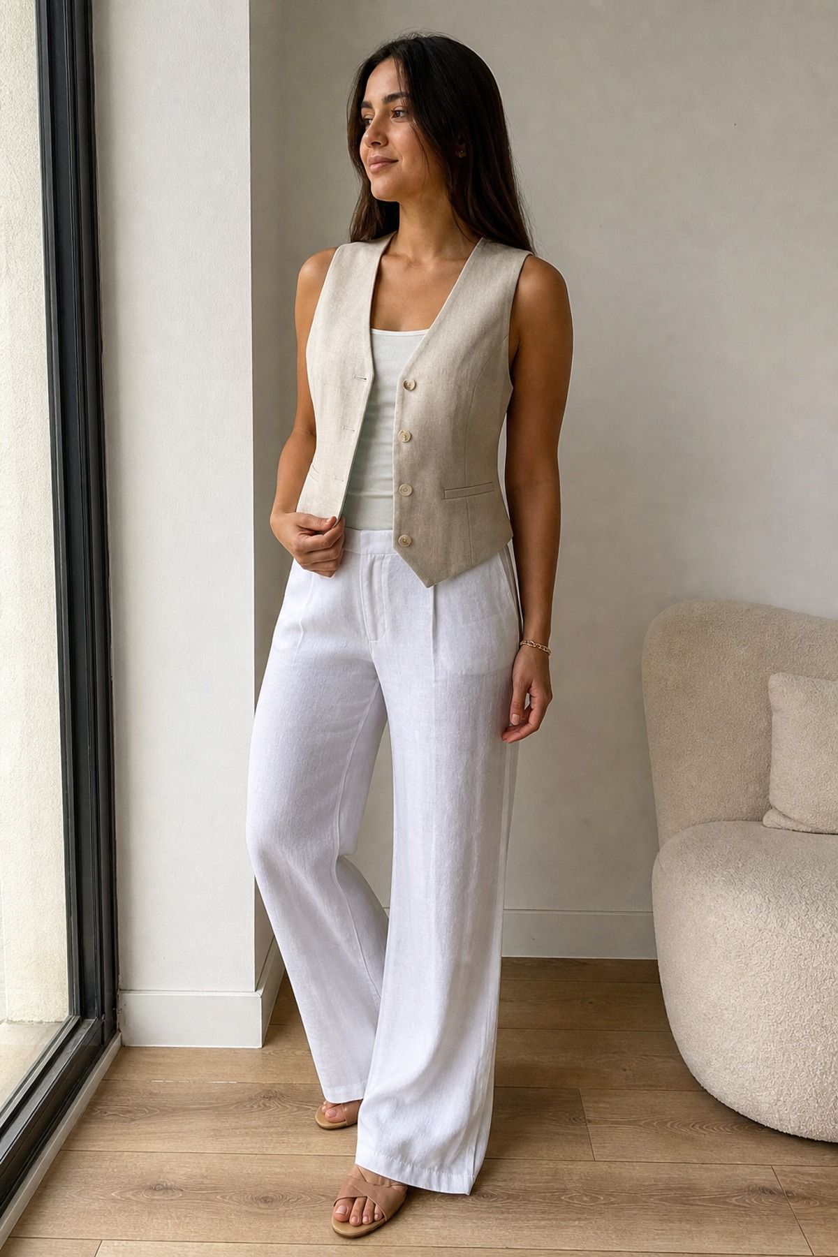 Woman wearing a beige vest with white trousers, a neutral outfit