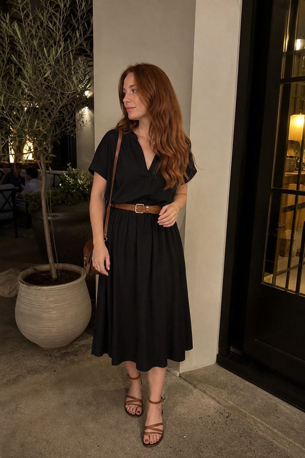 Woman wearing a black dress with a brown belt, a neutral outfit
