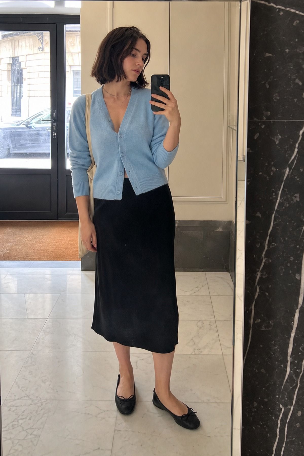 Woman wearing a baby blue cardigan with a black skirt, a pastel outfit