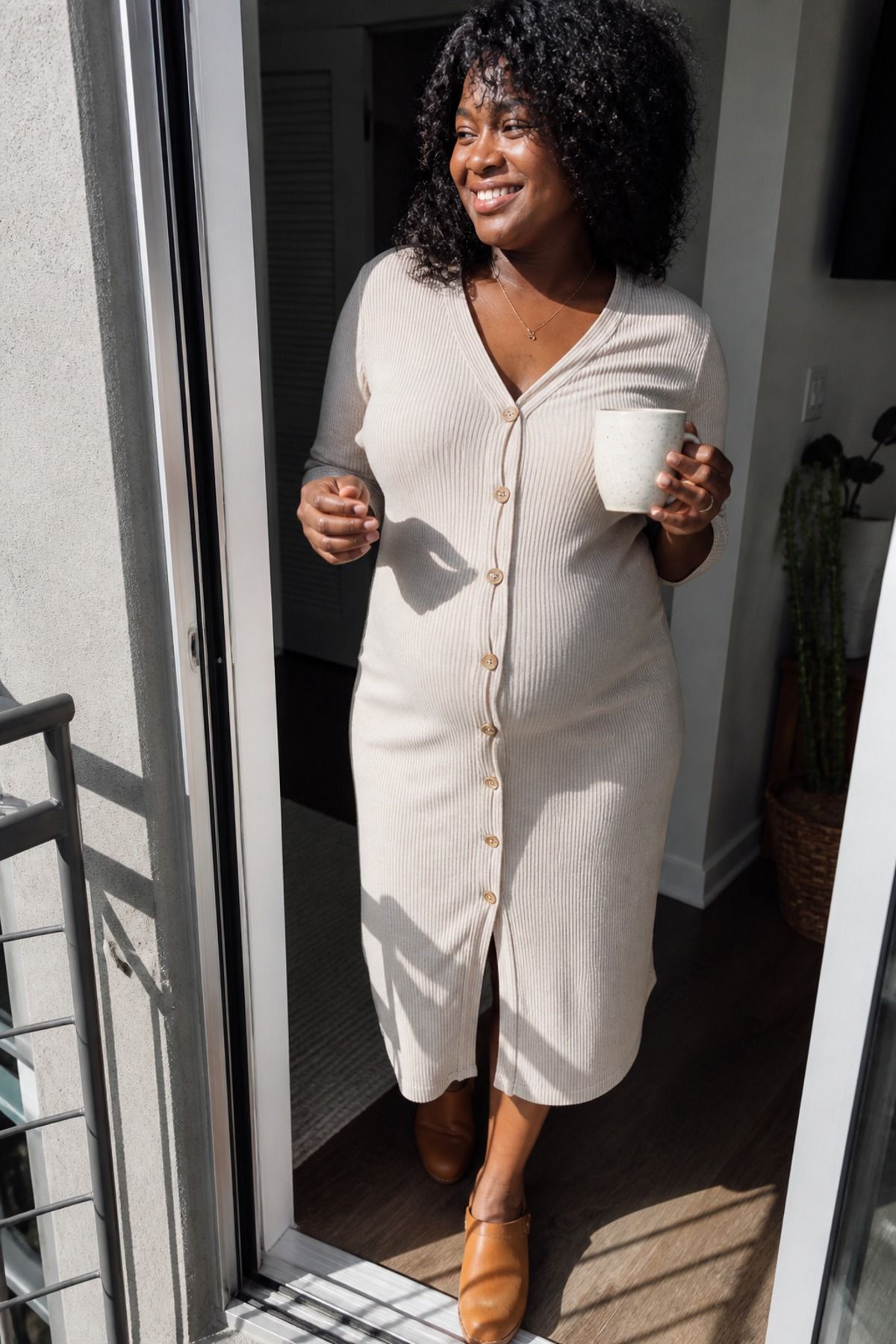 Woman wearing a button-front knit dress with clogs, a postpartum outfit