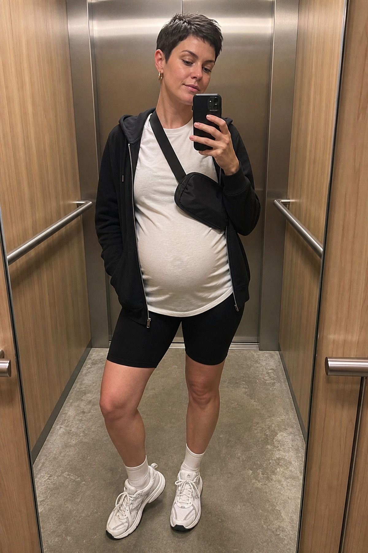 Woman wearing bike shorts with a tunic tee and zip hoodie, a pregnancy casual outfit