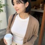 Woman wearing small gold huggie earrings with a simple everyday outfit