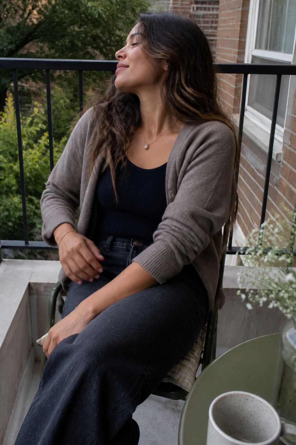 Woman wearing a pearl pendant necklace with a cardigan and jeans