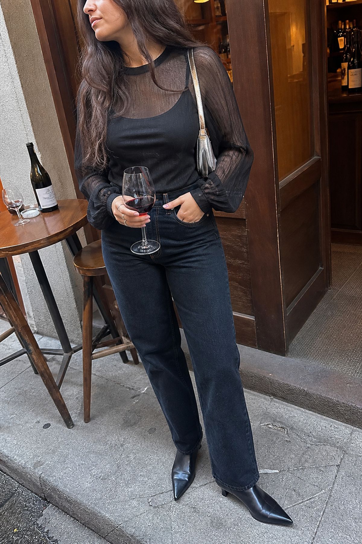 Woman wearing dark jeans with a sheer blouse, a birthday dinner outfit