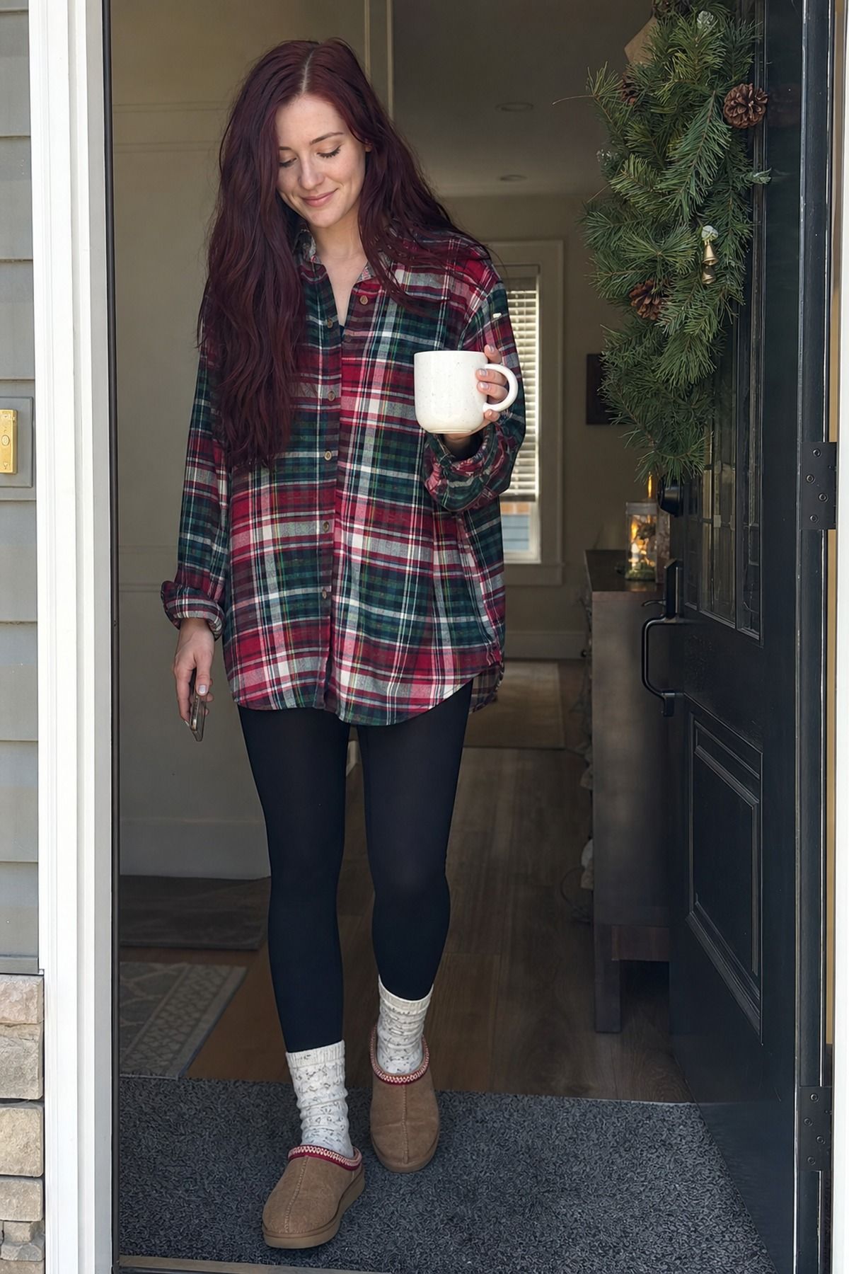Woman wearing a flannel shirt with soft black leggings, a Christmas morning outfit