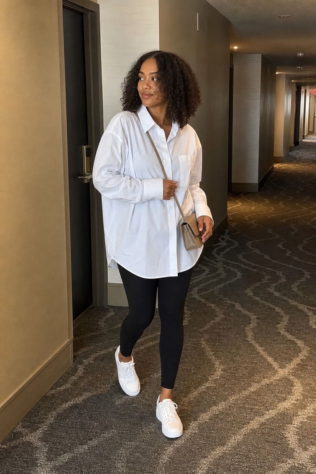 Woman wearing oversized oxford shirt with leggings and a crossbody bag for a spring travel outfit