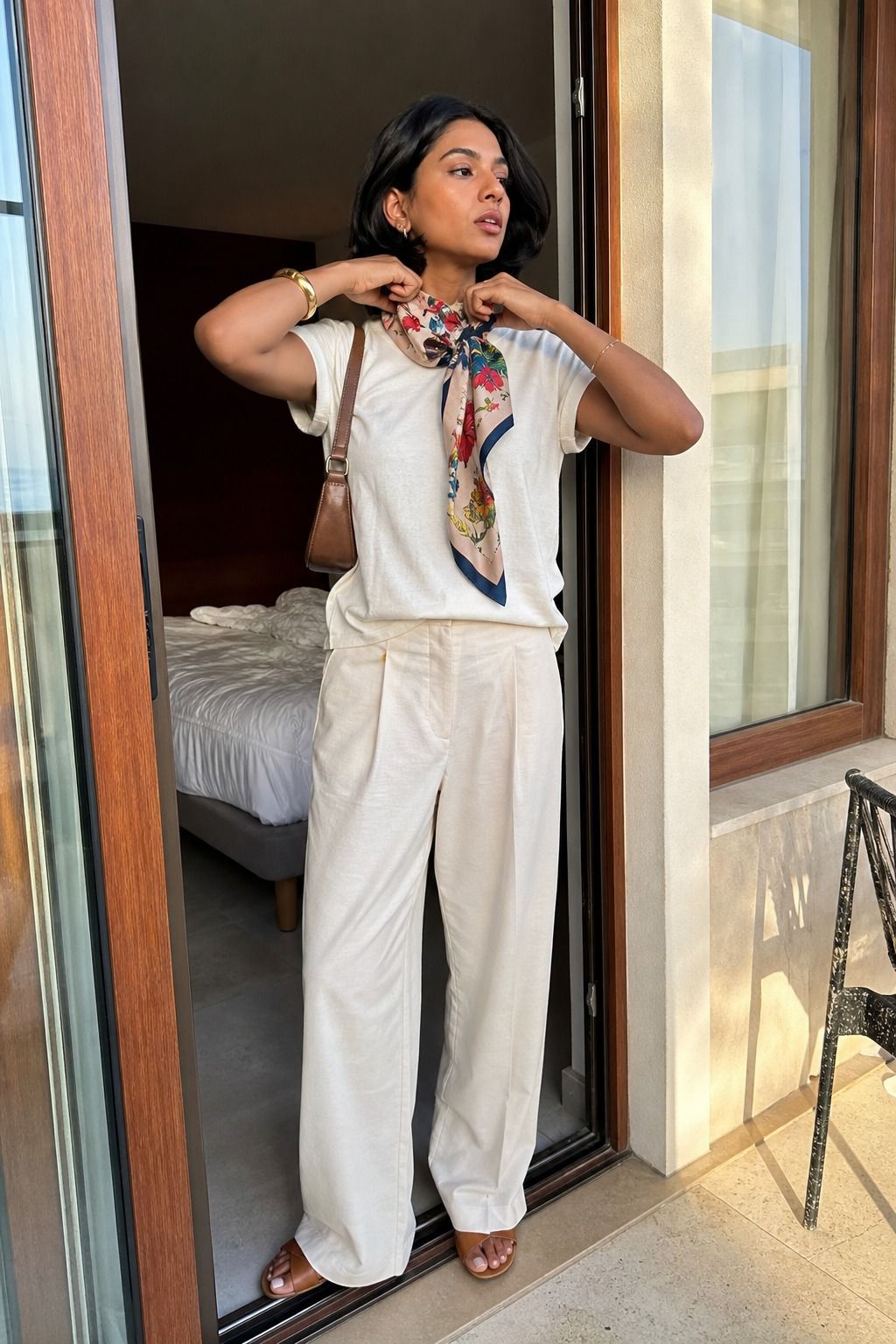 Woman wearing monochrome tee and trousers with a printed scarf for a spring travel outfit
